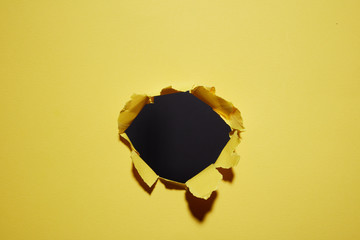 hole torn in the paper yellow background