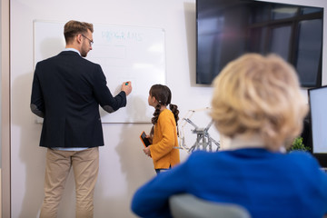 Male teacher writing on whiteboard, explaining programming