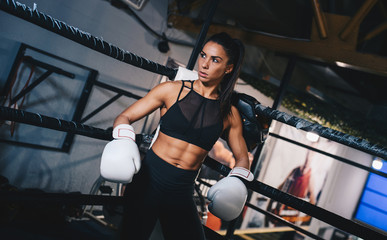 Female kickboxer resting on ring corner.