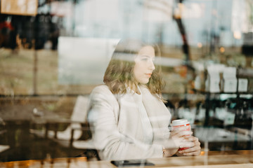 Fototapeta premium Beautiful young girl sitting and enjoing coffee in restaurant