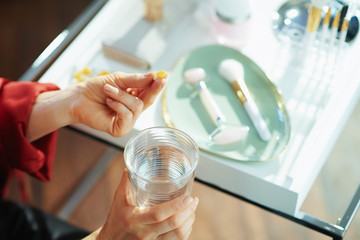 elegant woman with cup of water taking pill