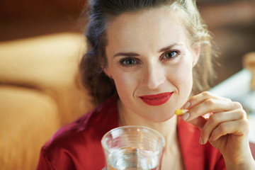 modern female with cup of water taking pill