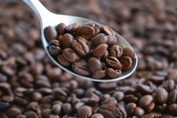Large spoon full of coffee beans over a textured background