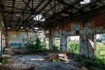 Old abandoned ruined industrial building overgrown by plants and trees
