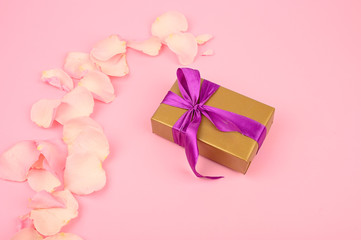 Gift box with bow on pink paper background. Greeting card for birthday, mothers day or valentines day.