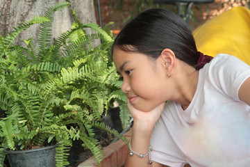 Young woman is watching  the fresh green leaves with little smile.