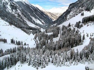Winter landscape. Canyon in the Austrian Alps. Austrian Tyrol, woodland and snow-covered trees, blue sky between the peaks of the mountains