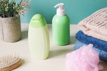Green shampoo bottle, liquid soap, wooden hair brush, colorful cotton towels and pink sponge. Organic bath products for skin and hair care
