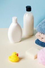 White shampoo bottle, coconut shower gel, cotton towels, natural soap, pink sponge and yellow rubber duck. Organic cosmetics. Baby care bath products