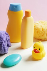 Obraz na płótnie Canvas Natural baby shampoo, shower gel, purple towel, sponge, soap bar and yellow rubber duck. Vertical photography baby care cosmetic products, toiletries set