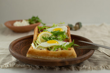 Belgian waffles with boiled quail eggs, mix of green leaves and cheese.