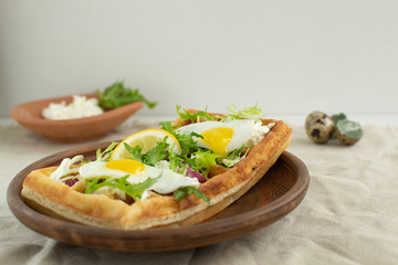 Belgian waffles with boiled quail eggs, mix of green leaves and cheese.