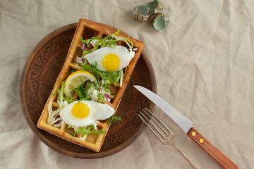 Belgian waffles with boiled quail eggs, mix of green leaves and cheese.