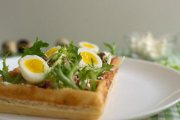 Belgian waffles with boiled quail eggs, mix of green leaves and cheese.