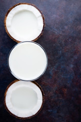 Coconut milk and coconut in glass on dark background. Coconut vegan milk non dairy with copy space. Healthy drink concept. Alternative milk. Flat lay