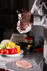 Chief chops and marinates pork. Professional chef in a kitchen of restaurant cooking.