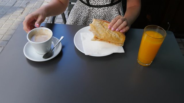 Woman have light Spanish breakfast, Bocadillo with jamon, hot coffee and orange juice. Lady eat sandwich and drink coffee, sitting at outdoor terrace of typical cafe in Barcelona