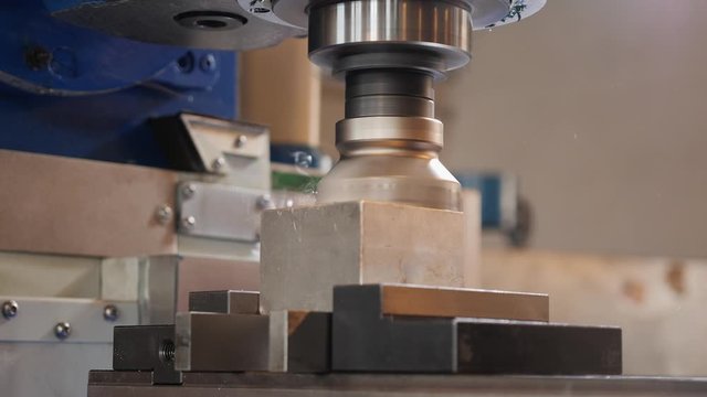 Industrial milling machine work on aluminium cube workpiece - low angle view, workbench moving