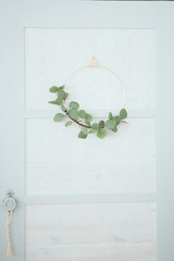 Pastel blue door with a floral wreath of green tristas. Element of the interior