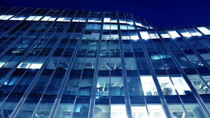 Night architecture - building with glass facade.Blue color of night lights. Modern building in  business district. Concept of economics, financial. Photo of commercial office building exterior. Abstra