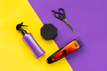 Beauty topic:  stylist scissors, hair wax, cutting machine and hairspray over purple and yellow background.  Fashion and style concept.