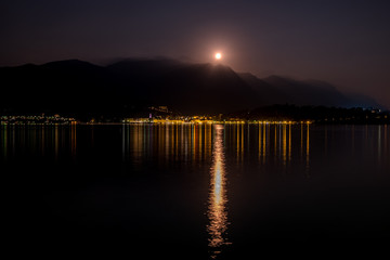 Lake Como reflects full moon and lights of Bellagio, Italy