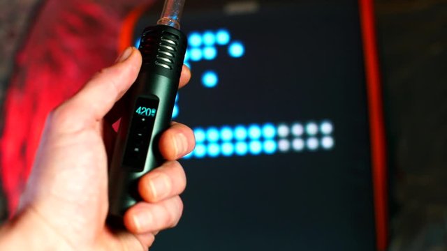 Close-up of a vaporizer with CBD cannabis in the hands of a man in a non-smoking place. The concept of electronic cigarettes. Stress relief in self-isolation COVID-19. Mental and physical relaxation.