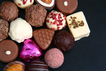 Close up of a selection of luxary chocolates, with a foil wrapped pink heart, which could be for a gift.