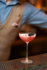 Expert barman is making cocktail at night club, close-up.