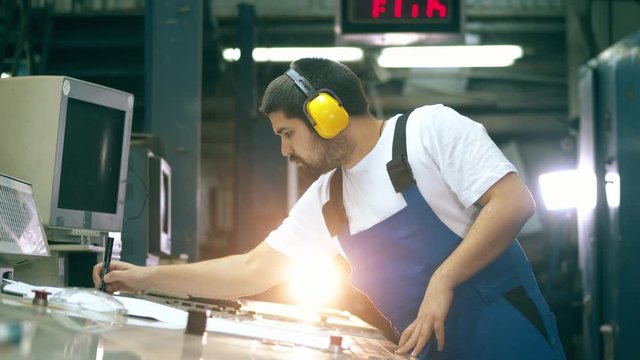 Male inspector is working with layouts and a control board. Engineer, worker at factory facility.
