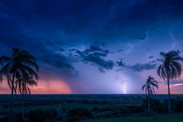 A thunder storm crosses the horizon behind the city of Bundaberg on sunset.