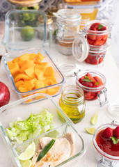 Batch cooking scene full of container glasses with delicious meal inside them on a white wooden...