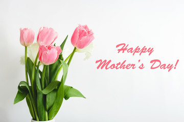Happy Mothers Day text on gift card in flower bouquet on white background. Greeting card for Mom. Flower delivery, Congratulations card in flowers for women. Greeting card in pink tulips.