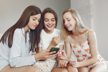 Girls in a pajamas. Friends have fun at home. Ladies eating popcorn.