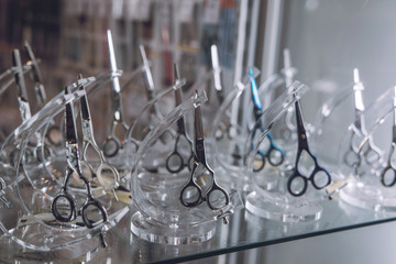 Stylish Professional Barber Scissors, Hair Cutting and Thinning Scissors in retail shop glass window display showcase. Hairdressing tools in the barber shop. Haircut accessories.