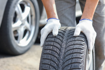 a After a breakdown, a person changes a wheel on a car to another wheel with a wrench