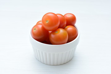 Fresh cherry tomato, displayed in containers on white wooden background