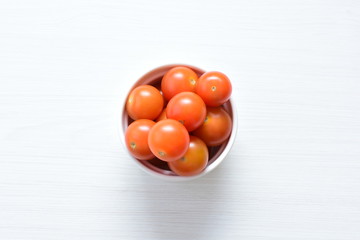 Fresh cherry tomato, displayed in containers on white wooden background