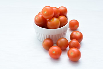 Fresh cherry tomato, displayed in containers on white wooden background