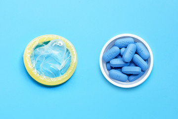 Condom with PrEP ( Pre-Exposure Prophylaxis) used to prevent HIV, in plastic pill bottle cap on blue background. Save sex - obrazy, fototapety, plakaty