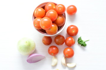 Fresh cherry tomato, displayed in containers on white wooden background