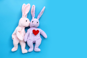 Rabbit toys kissing with red heart on blue background. Valentine's Day