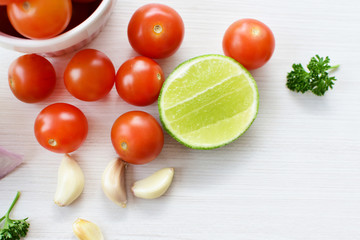 Fresh cherry tomato, displayed in containers on white wooden background