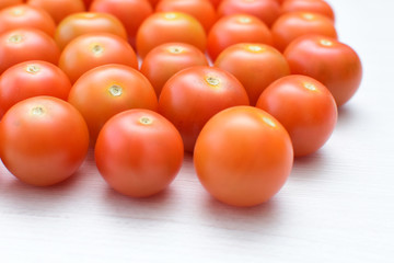 Fresh cherry tomato, displayed in containers on white wooden background