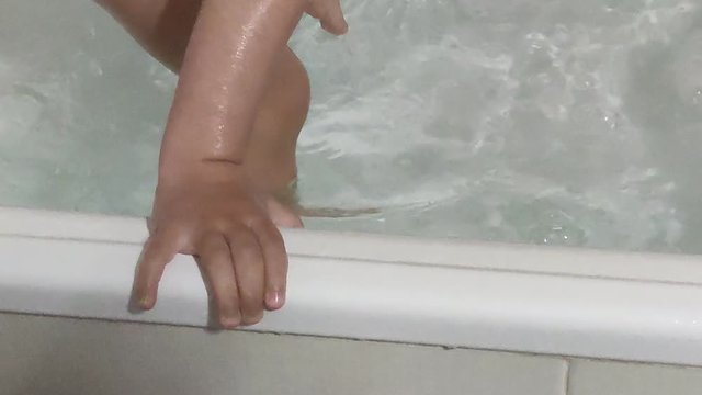 Little boy in the bath splashing water all over.