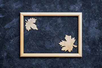 Wooden frame and wooden two tree leaf on dark surface. Fall concept. Flat lay, top view, copy space