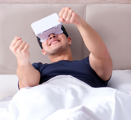 Wife and husband with virtual reality goggles in the bed