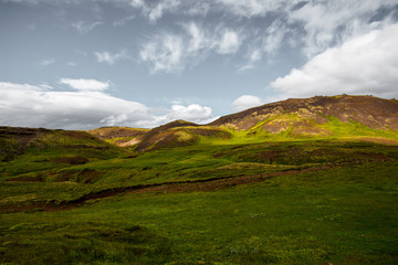 Wonderful icelandic nature landscape. View from the top. High mountains, mountain river and green grassland. Green meadows. Iceland.