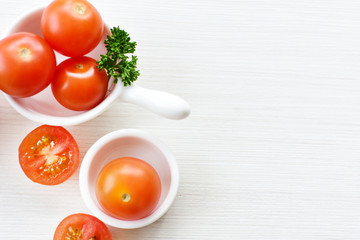Fresh cherry tomato, displayed in containers on white wooden background