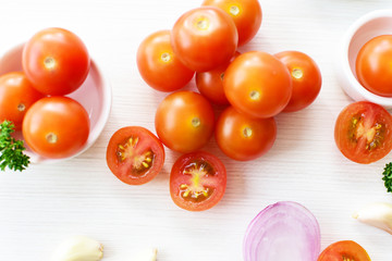 Fresh cherry tomato, displayed in containers on white wooden background
